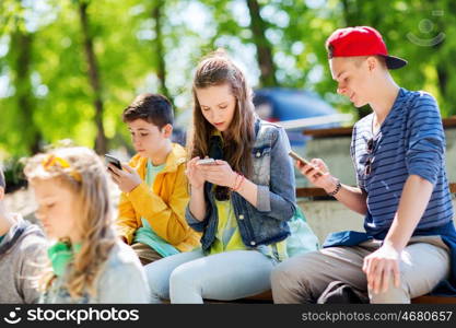 technology, internet addiction and people concept - happy teenage friends with smartphones outdoors