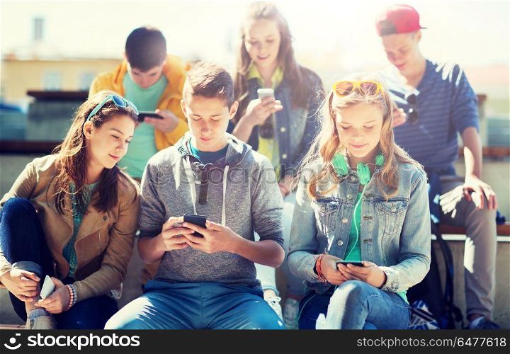 technology, internet addiction and people concept - happy teenage friends with smartphones outdoors. happy teenage friends with smartphones outdoors. happy teenage friends with smartphones outdoors