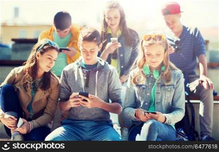 technology, internet addiction and people concept - happy teenage friends with smartphones outdoors. happy teenage friends with smartphones outdoors. happy teenage friends with smartphones outdoors