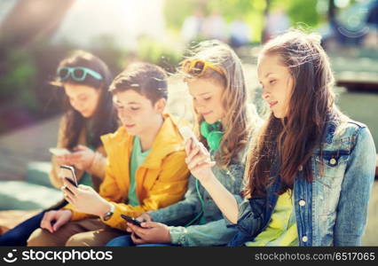 technology, internet addiction and people concept - happy teenage friends with smartphones outdoors. happy teenage friends with smartphones outdoors. happy teenage friends with smartphones outdoors