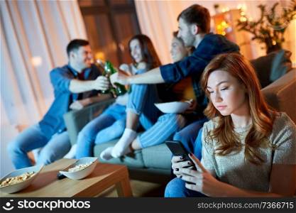 technology, internet addiction and people concept - sad young woman with smartphone at home friends party in evening. sad young woman with smartphone at home party