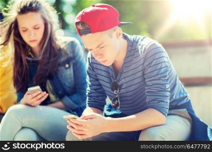 technology, internet addiction and people concept - teenage friends with smartphones outdoors. teenage friends with smartphones outdoors. teenage friends with smartphones outdoors
