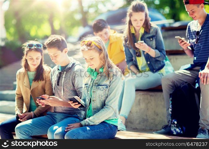 technology, internet addiction and people concept - teenage friends with smartphones outdoors. teenage friends with smartphones outdoors. teenage friends with smartphones outdoors