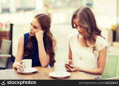 technology, internet addiction, lifestyle, friendship and people concept - young women or teenage girls with smartphones and coffee cups at cafe outdoors