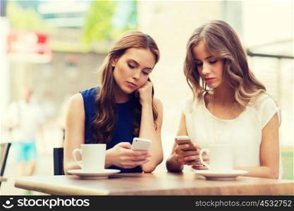 technology, internet addiction, lifestyle, friendship and people concept - young women or teenage girls with smartphones and coffee cups at cafe outdoors
