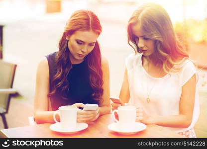 technology, internet addiction, lifestyle, friendship and people concept - young women or teenage girls with smartphones and coffee cups at cafe outdoors. women with smartphones and coffee at outdoor cafe