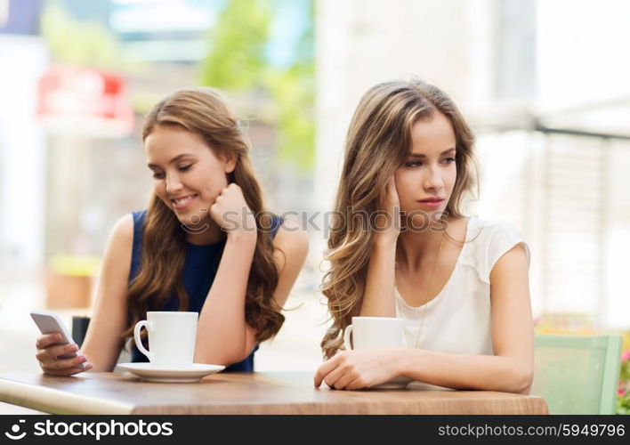 technology, internet addiction, lifestyle, friendship and people concept - young women or teenage girls with smartphones and coffee cups at cafe outdoors