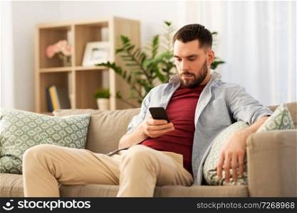 technology, internet and communication concept - man using smartphone at home. man using smartphone at home