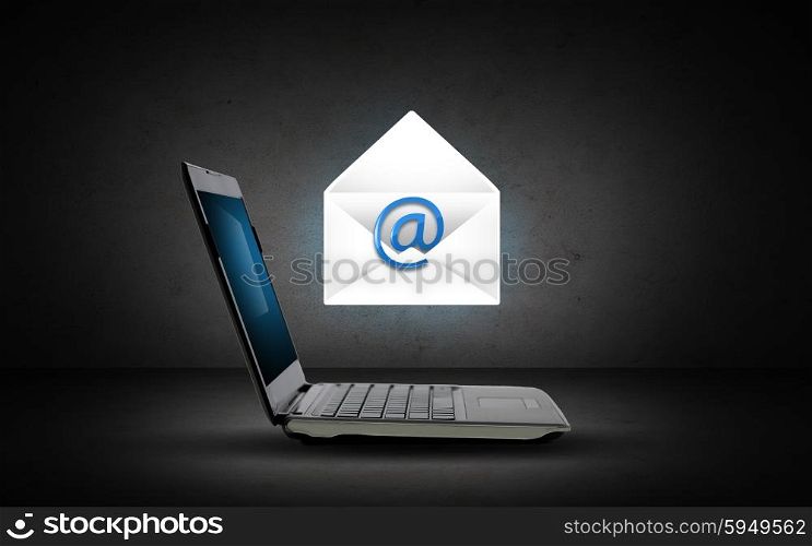technology, internet and communication concept - open laptop computer with e-mail icon and virtual letter over dark gray background