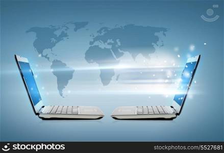 technology, internet and connection concept - two laptop computers with world map hologram