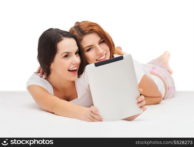 technology, internet and entertainment concept - two smiling teenage girls in pajamas with tablet computer