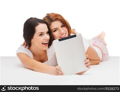 technology, internet and entertainment concept - two smiling teenage girls in pajamas with tablet computer
