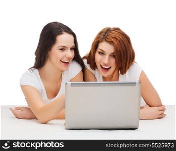 technology, internet and entertainment concept - two smiling teenage girls in white t-shirts with laptop computer