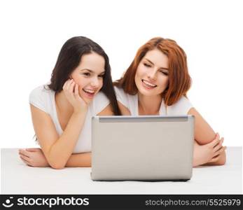 technology, internet and entertainment concept - two smiling teenage girls in white t-shirts with laptop computer
