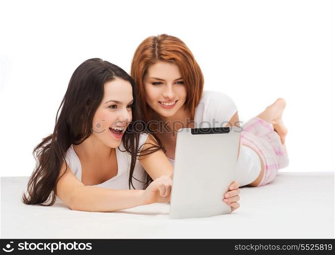 technology, internet and entertainment concept - two smiling teenage girsl in pajamas with tablet pc computer