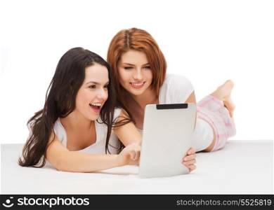 technology, internet and entertainment concept - two smiling teenage girsl in pajamas with tablet pc computer