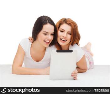 technology, internet and entertainment concept - two smiling teenage girsl in white t-shirts with tablet pc computer