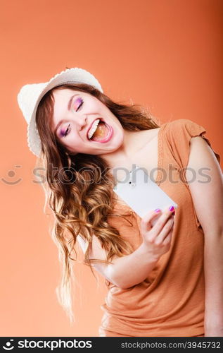 Technology internet and happiness concept. Happy summer woman taking self picture selfie with smartphone camera orange background