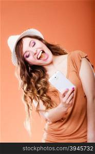 Technology internet and happiness concept. Happy summer woman taking self picture selfie with smartphone camera orange background