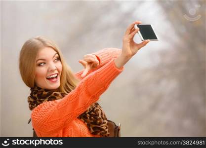 Technology internet and happiness concept. Woman content girl taking self picture selfie with smartphone camera while walking outdoors in autumn park in foggy day