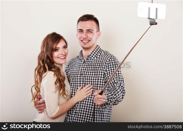 Technology internet and happiness concept. Young couple taking self picture selfie with smartphone camera gray background