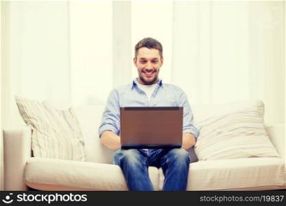 technology, internet and lifestyle concept - smiling man working with laptop at home