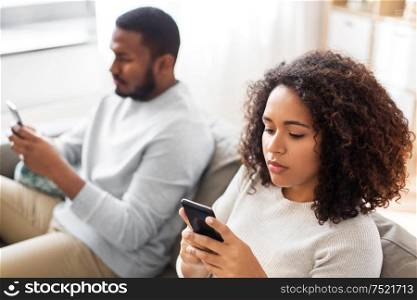 technology, internet and people concept - african american couple with smartphone at home. african american couple with smartphone at home