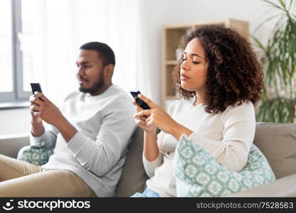 technology, internet and people concept - african american couple with smartphone at home. african american couple with smartphone at home