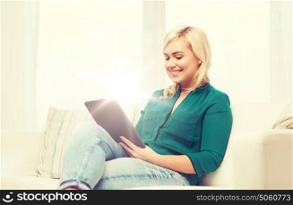 technology, internet and people concept concept - smiling woman sitting on couch with tablet pc computer at home. smiling woman with tablet pc at home