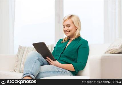 technology, internet and people concept concept - smiling woman sitting on couch with tablet pc computer at home