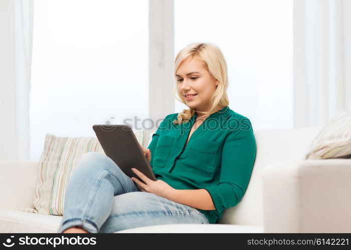 technology, internet and people concept concept - smiling woman sitting on couch with tablet pc computer at home