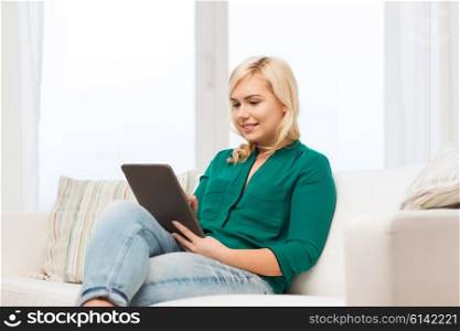 technology, internet and people concept concept - smiling woman sitting on couch with tablet pc computer at home