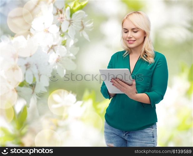 technology, internet and people concept concept - smiling woman with tablet pc computer over natural cherry blossom background