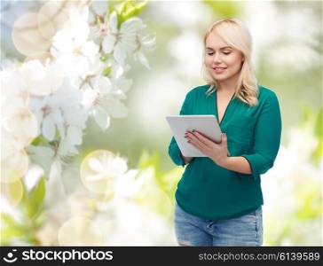 technology, internet and people concept concept - smiling woman with tablet pc computer over natural cherry blossom background