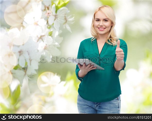 technology, internet and people concept concept - smiling woman with tablet pc computer showing thumbs up over natural cherry blossom background
