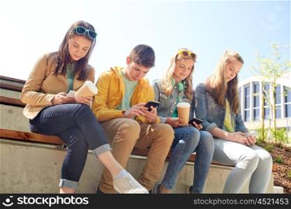 technology, internet and people concept - group of happy teenage friends with smartphone and coffee cups outdoors
