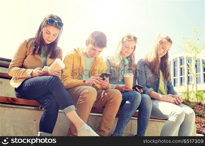 technology, internet and people concept - group of happy teenage friends with smartphone and coffee cups outdoors. teenage friends with smartphone and coffee cups. teenage friends with smartphone and coffee cups