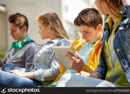 technology, internet and people concept - group of teenage friends or high school students with tablet pc computer outdoors