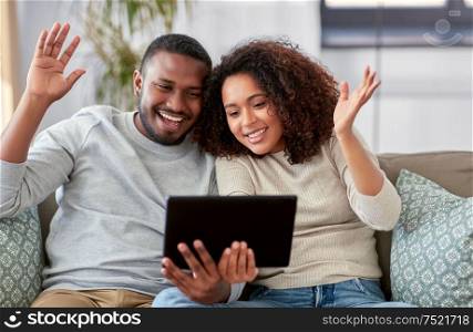 technology, internet and people concept - happy african american couple with tablet computer having video call at home. african couple with tablet pc having video call