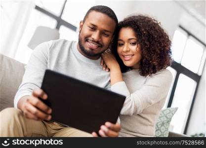 technology, internet and people concept - happy african american couple with tablet computer at home. african american couple with tablet pc at home