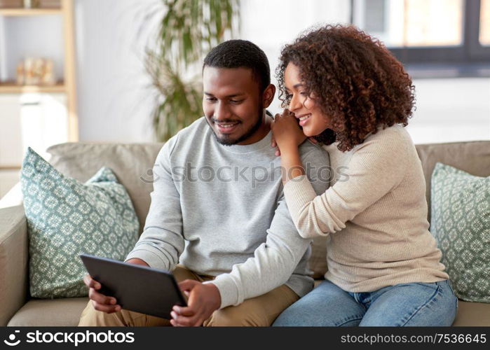 technology, internet and people concept - happy african american couple with tablet computer at home. african american couple with tablet pc at home