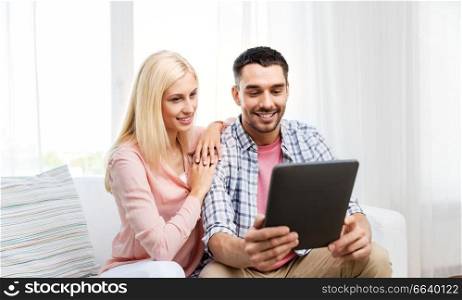 technology, internet and people concept - happy couple with tablet pc computer at home. happy couple with tablet computer at home