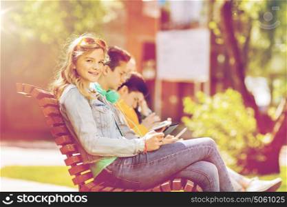 technology, internet and people concept - happy girl with tablet pc computer and group of teenage friends or students outdoors. happy girl with tablet pc computer outdoors