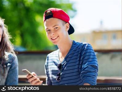 technology, internet and people concept - happy teenage boy with smartphone outdoors