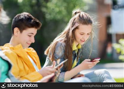 technology, internet and people concept - happy teenage boy with tablet pc computer and girl with smartphone outdoors