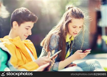 technology, internet and people concept - happy teenage boy with tablet pc computer and girl with smartphone outdoors. happy teenage friends with gadgets outdoors. happy teenage friends with gadgets outdoors