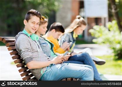 technology, internet and people concept - happy teenage boy with tablet pc computer and headphones outdoors