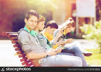 technology, internet and people concept - happy teenage boy with tablet pc computer and headphones outdoors. happy teenage boy with tablet pc and headphones
