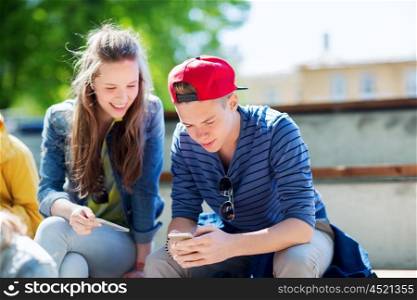 technology, internet and people concept - happy teenage friends with smartphones outdoors