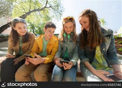 technology, internet and people concept - happy teenage friends with smartphones outdoors